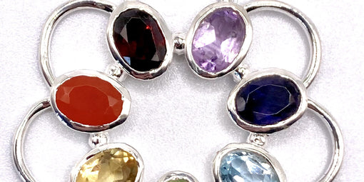 Various colorful gemstones set in silver thimble jewelry design, showcasing artistic craftsmanship and elegance.