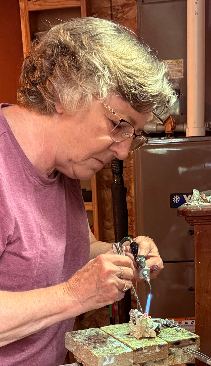 Artisan crafting handmade sterling silver thimbles with a torch in a workshop, showcasing thimble-making skills.