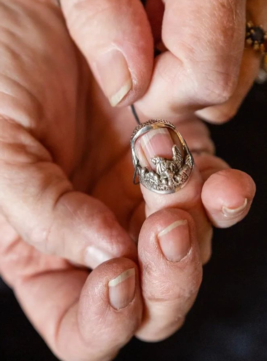 Hand holding a sterling silver thimble, showcasing intricate design details, ideal for sewing and thimble collecting.