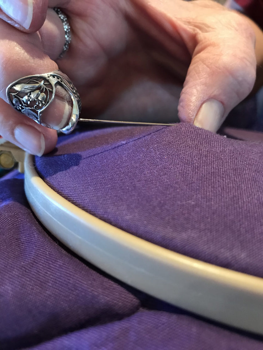 Lily of the Valley Thimble on fabric during sewing, showcasing sterling silver craftsmanship for quilters.