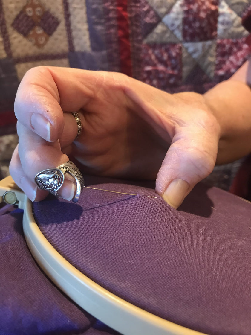 Lily of the Valley Thimble in use for embroidery, showcasing sterling silver craftsmanship and sewing tool functionality.
