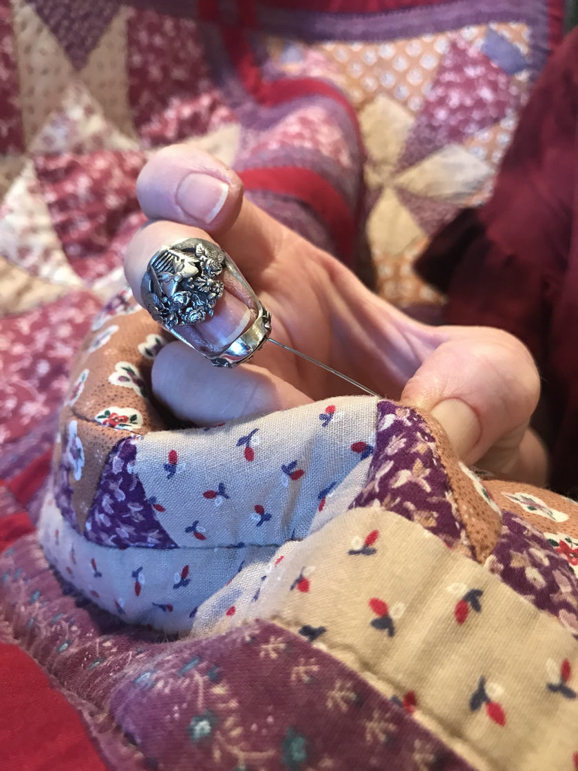 Close-up of a Flower Basket Thimble in use on a quilt, showcasing heirloom quality and intricate design.