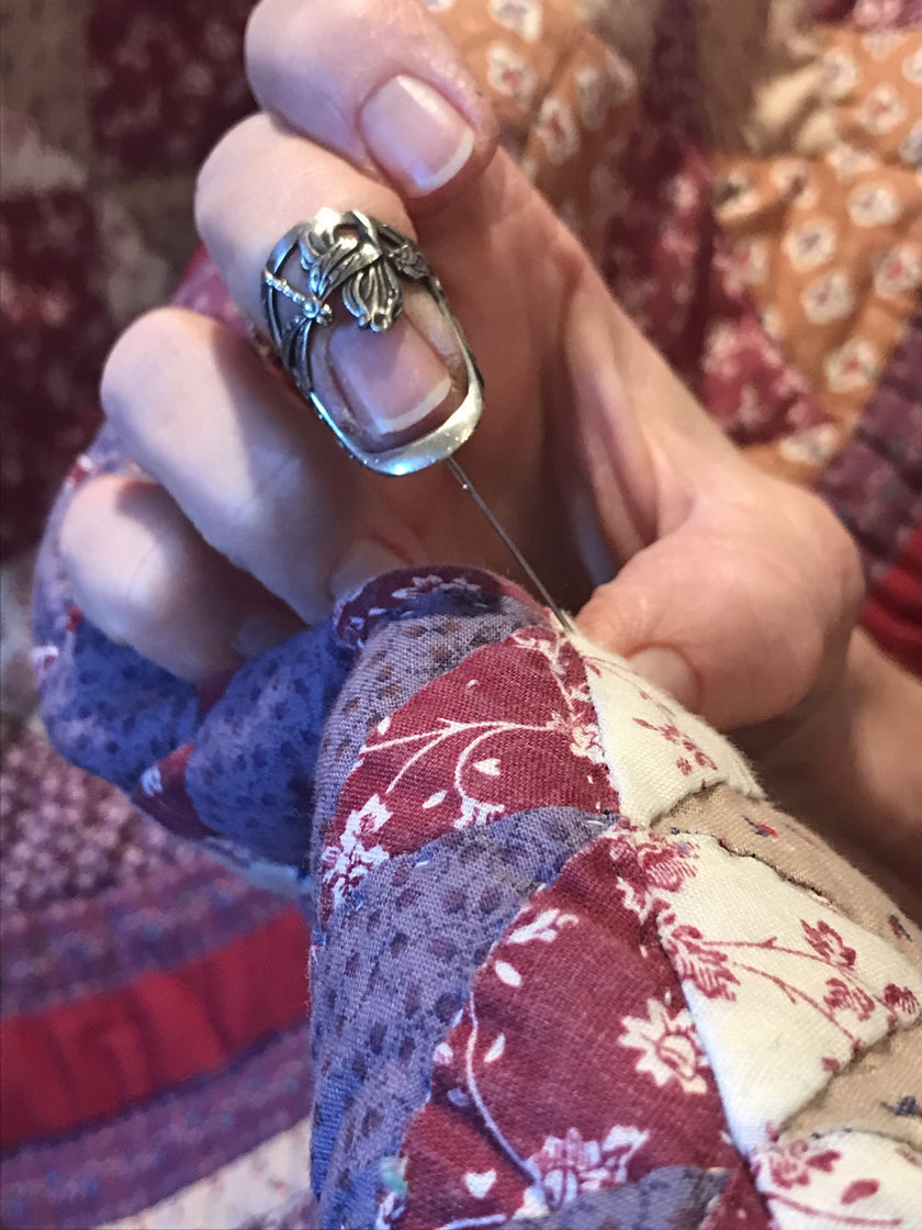 Person using a Dragonfly and Iris Thimble while sewing, showcasing sterling silver craftsmanship and quilting techniques.