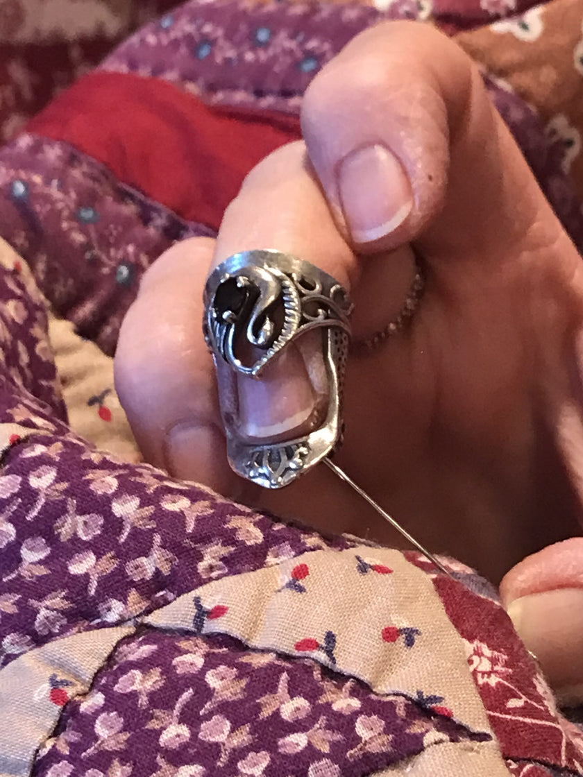 Swan Thimble shown on a finger, featuring intricate sterling silver design, ideal for sewing and quilting projects.