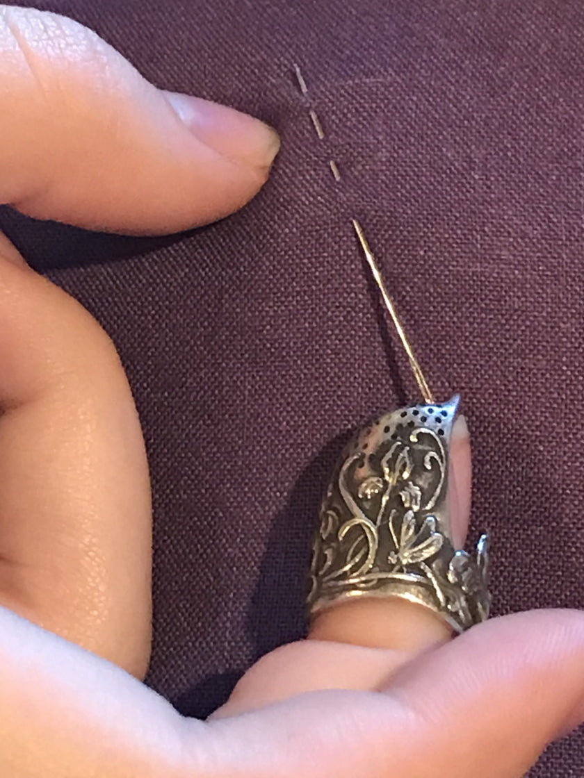 Dragonfly and Iris Thimble in use while sewing with a needle on fabric, showcasing craftsmanship and detail.
