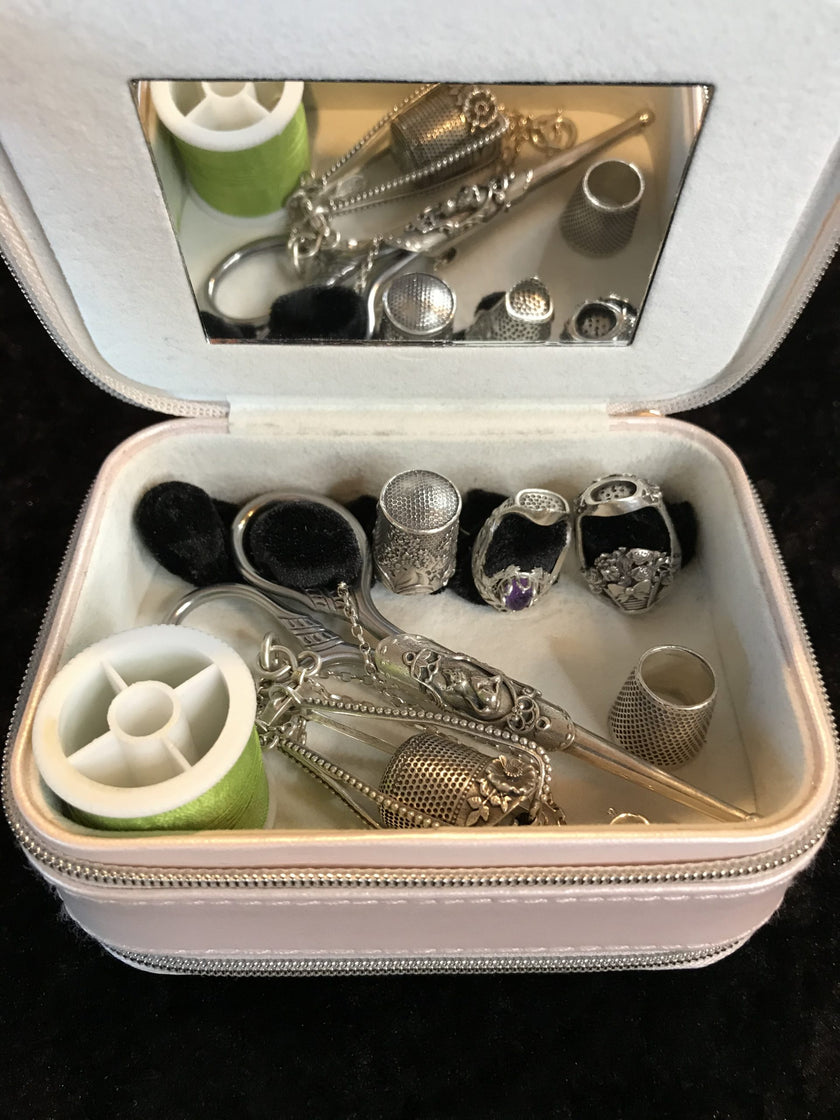Sewing Travel Kit with silver thimbles, tools, and accessories in a zippered case for crafting and sewing.